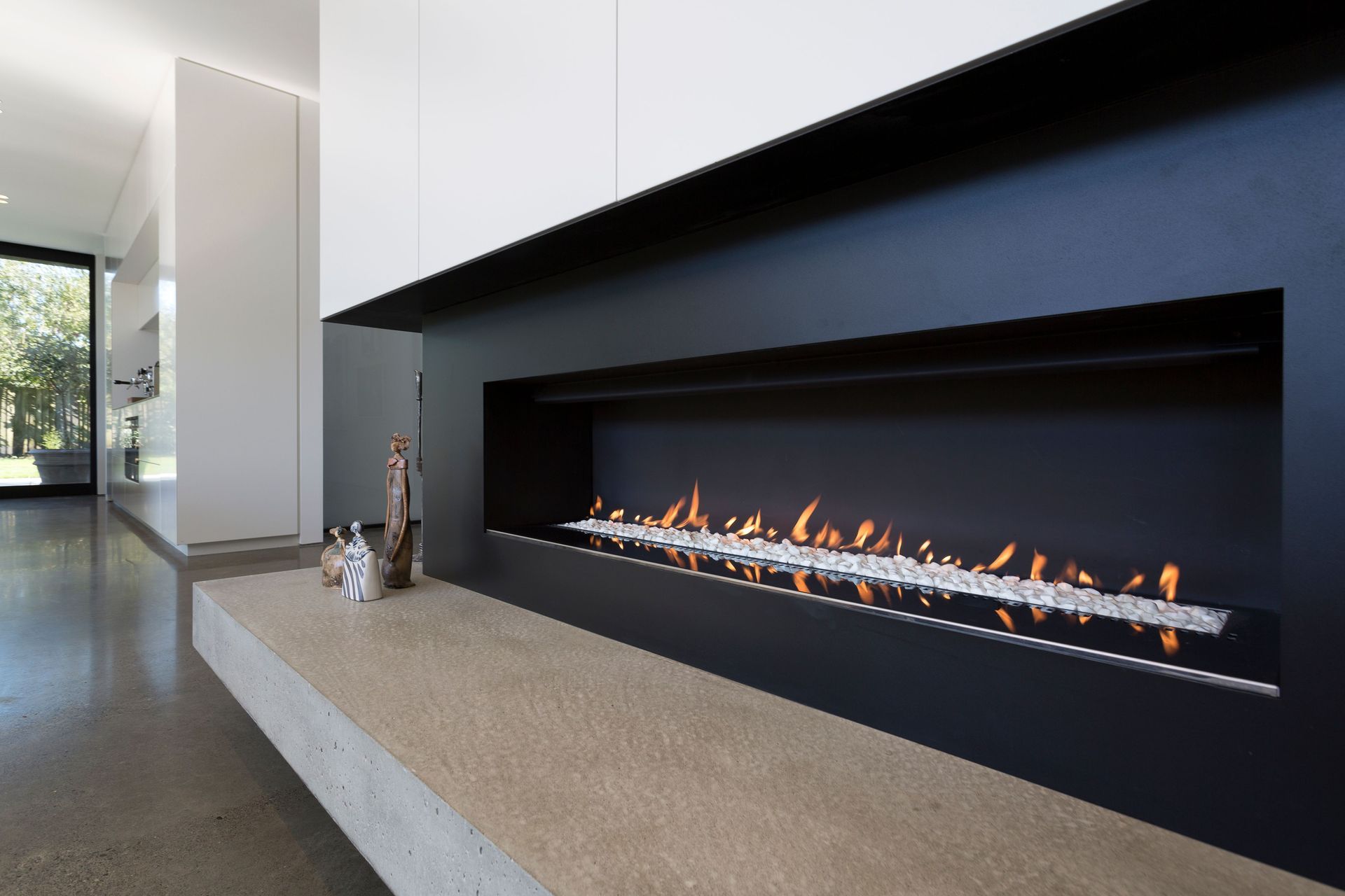 In the lounge area, the fireplace has all-black surrounds with a solid concrete hearth.