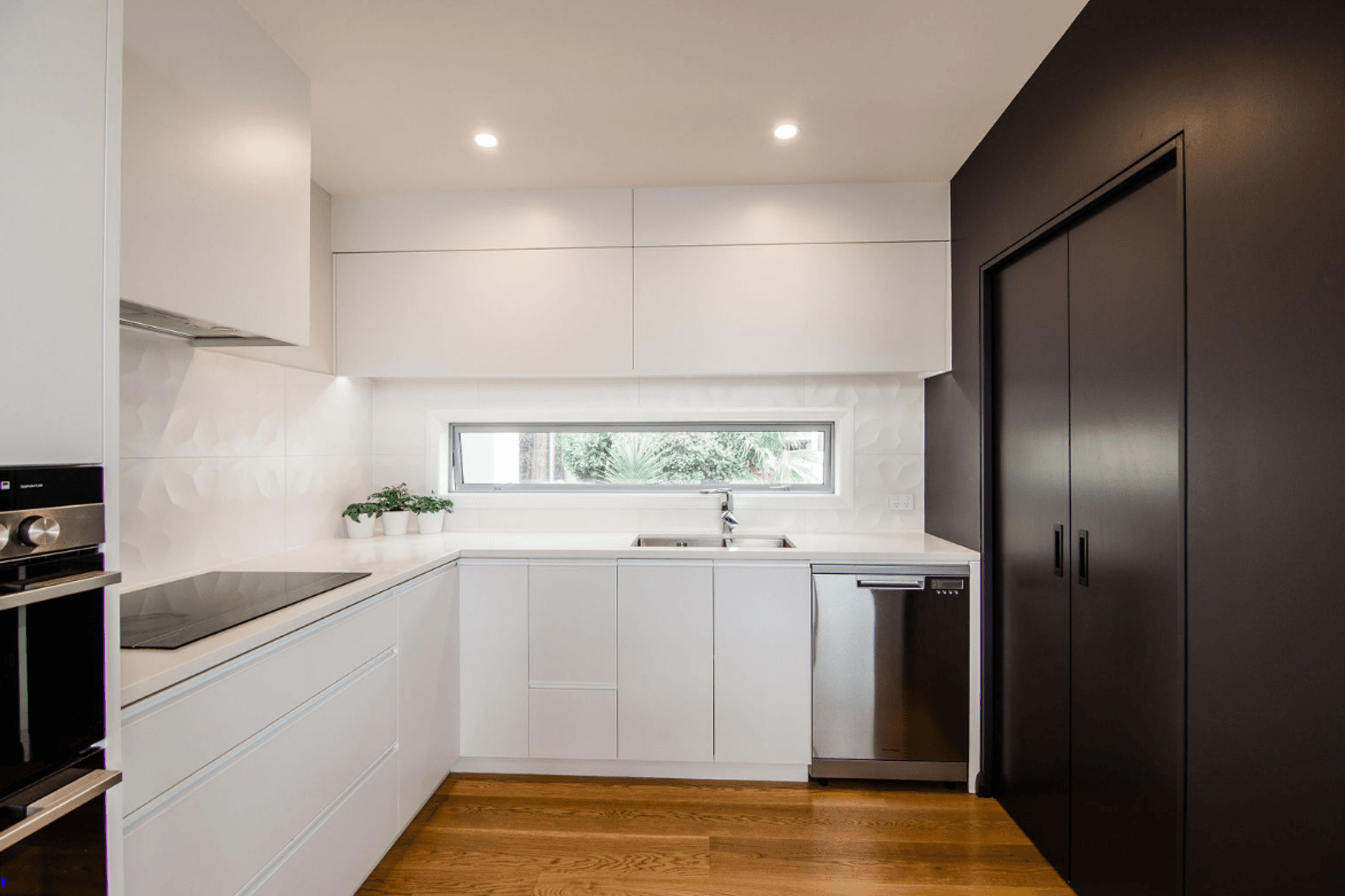 Sleek Black and White kitchen, the scullery is incorporated behind the black cavity sliders.