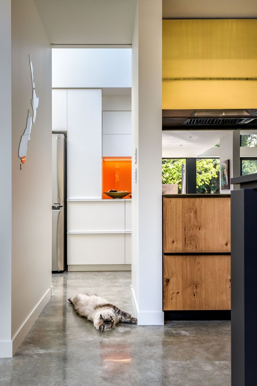 Looking through the kitchen to the scullery. Timber, gold and orange add warmth to the grey and white material palette.