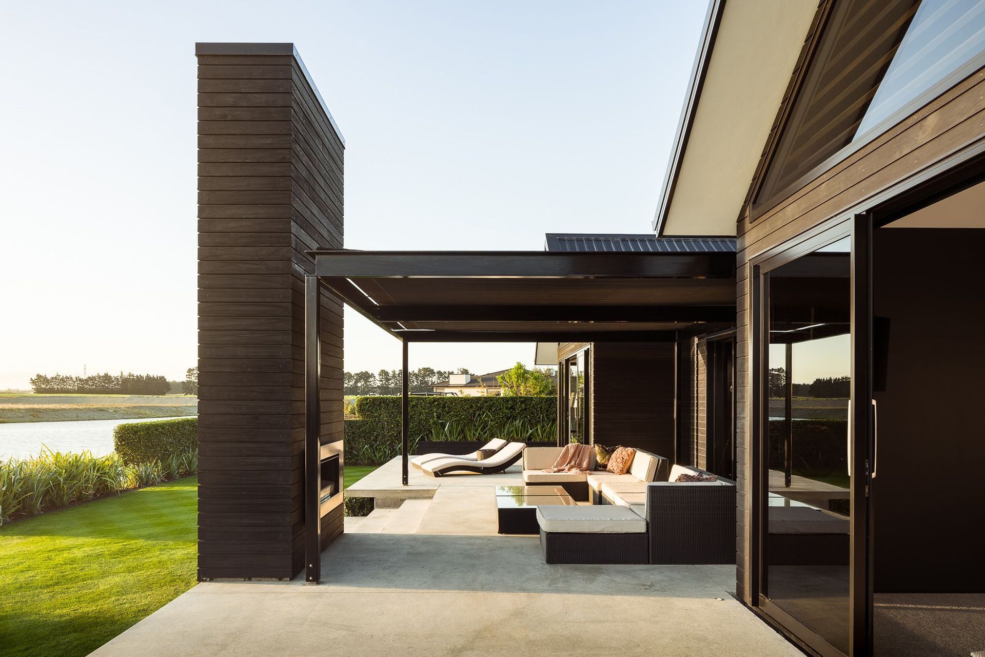 An outdoor fireplace, clad in dark-stained cedar echoes two other fireplaces inside the home. 