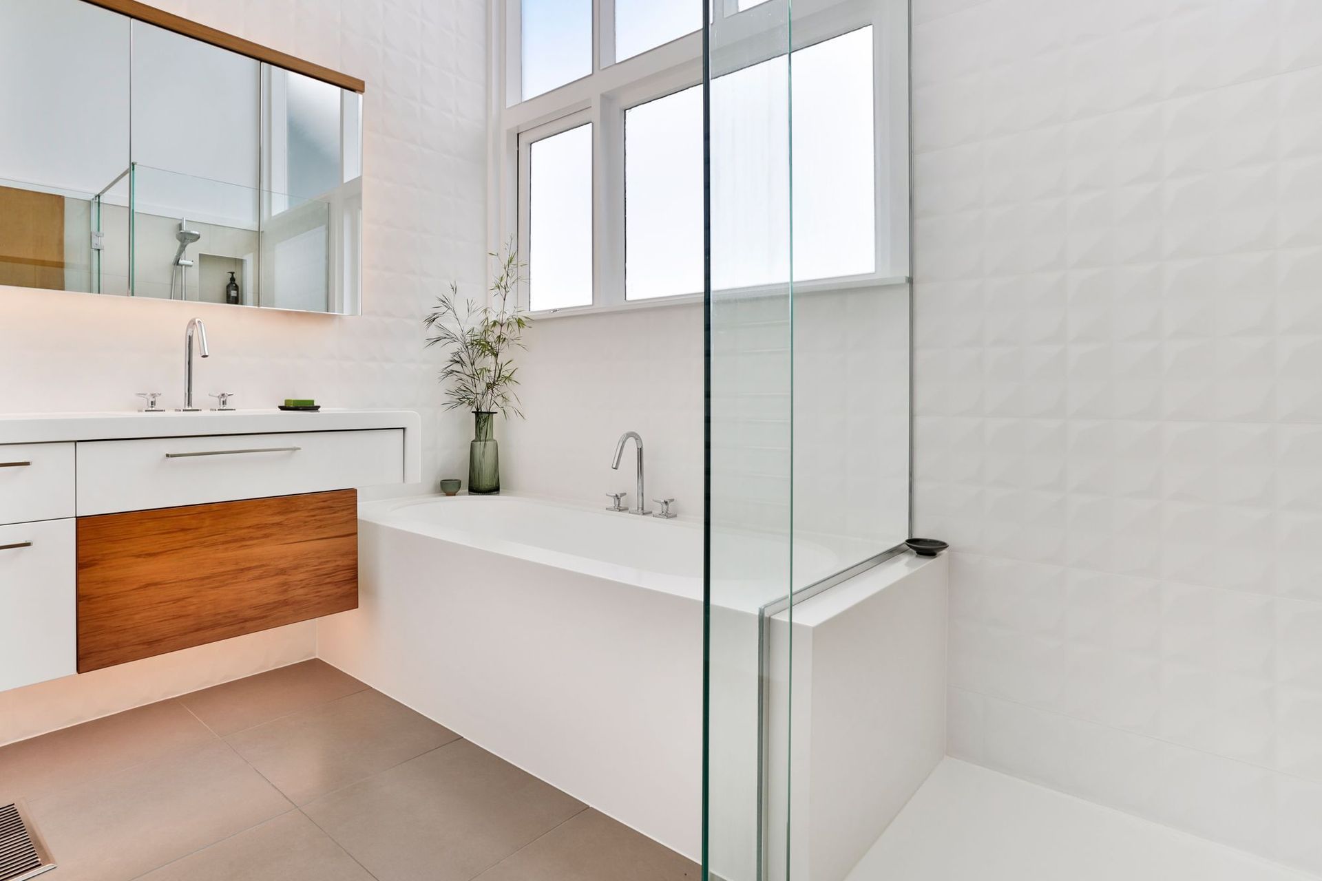This natural light bathed bathroom delivers a sense of fresh and calm while functioning on a practical level as an easy-clean, monolithic design, seamlessly sealed in Corian.  Its geometric tiles, touches of timber and seamless forms, portray a soulful ch