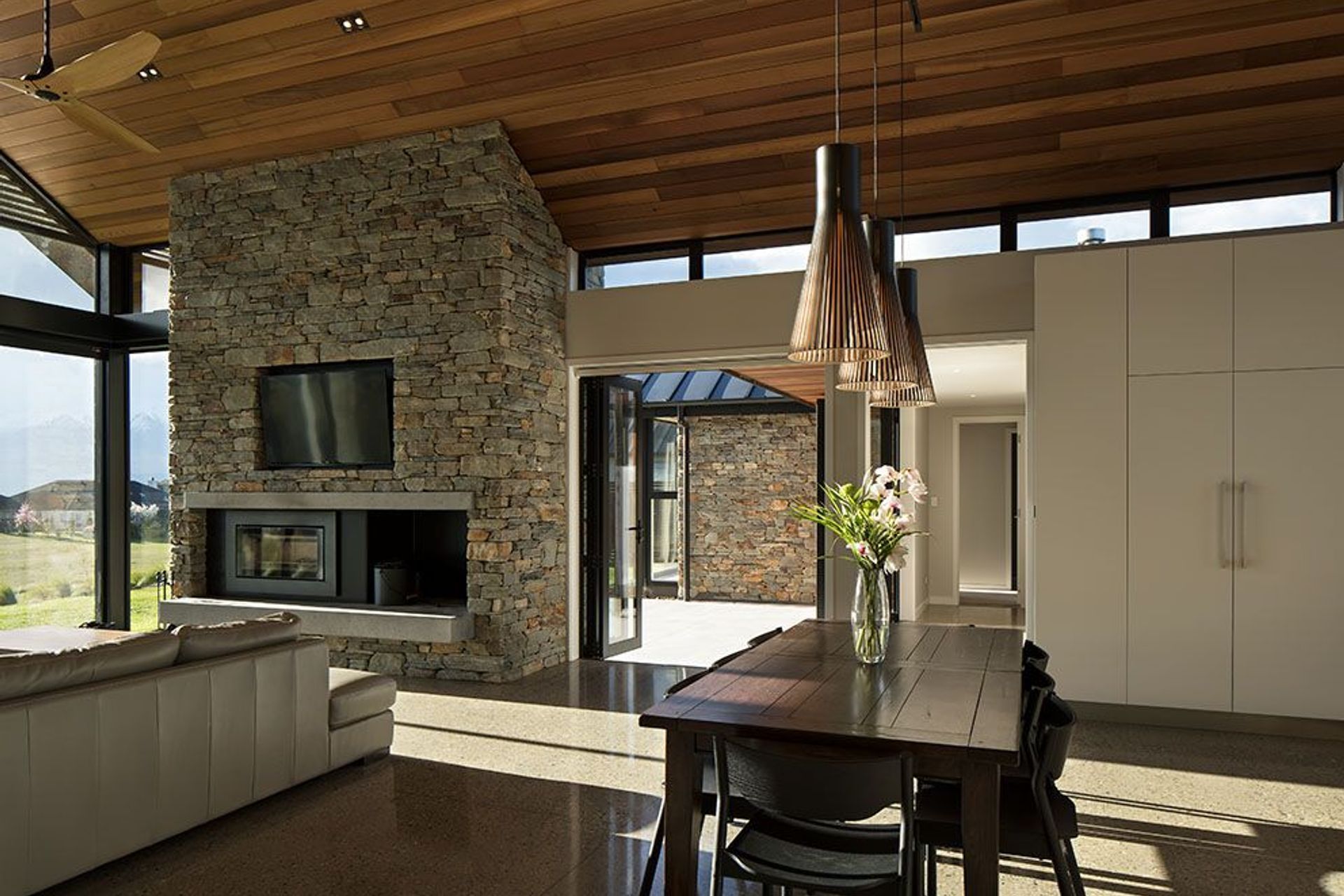 Much as the exterior form is reflected in the high volume interior spaces, so too is the external palette carried into the interior, with stonework and cedar featuring in the main living room.