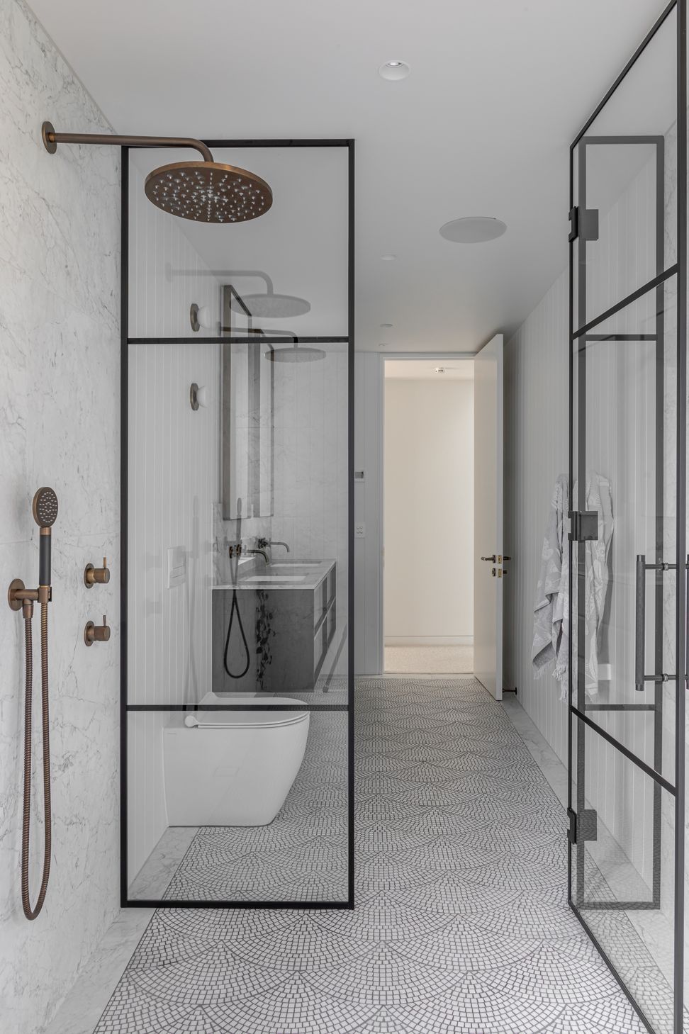 Generous airy bathrooms are tiled in a fan pattern with light marble mosaic