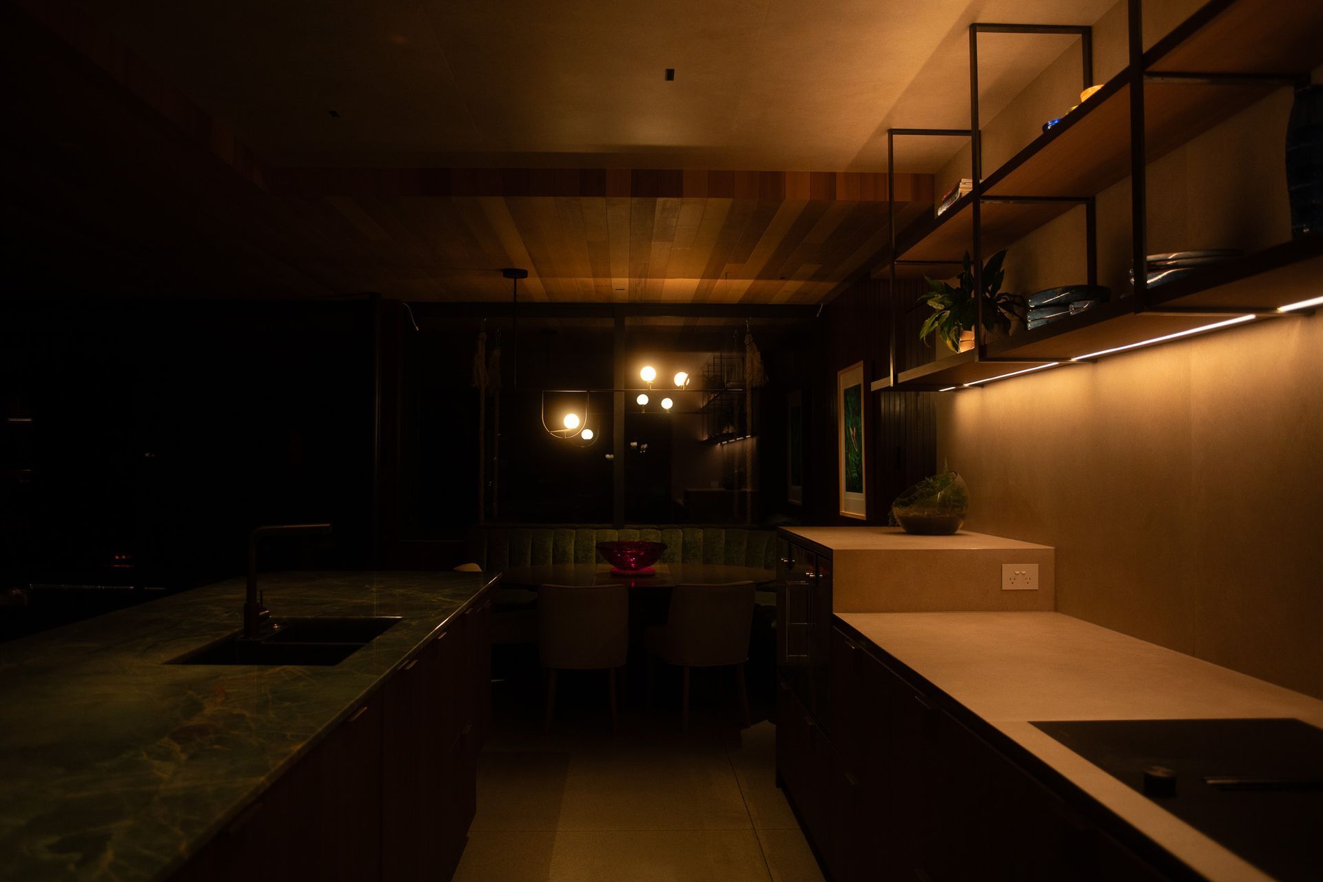 A seamless transition between kitchen and dining, where layered lighting creates a space that adapts to every occasion. Integrated LED detailing within the kitchen provides subtle ambient illumination, while the sculptural Artemide Yanzi suspension pendant becomes a defining feature above the dining area.