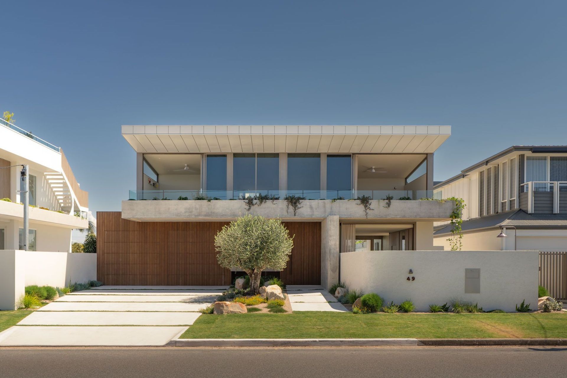 House on Pacific - Exterior. Street elevation with a floating upper level and an olive tree in the front garden.