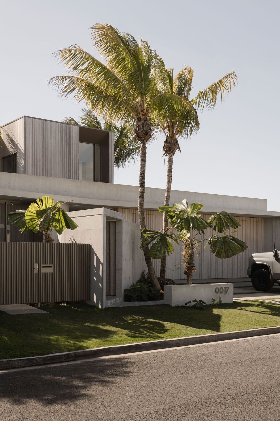 Solmere - Exterior. Timber clad upper level rising above the concrete base and tropical garden.