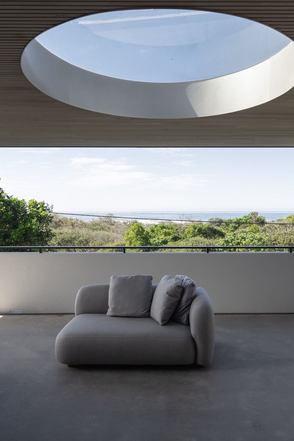 Decade House - Balcony. Covered balcony with an oval skylight and views over the treetops to the ocean.