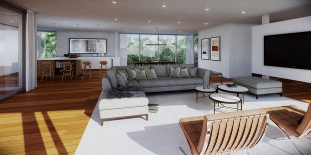 A spacious, contemporary open-plan living room with a large grey sectional sofa, white rug, sculptural lounge chairs, round nesting coffee tables, and a wall-mounted television. Warm timber flooring extends into the adjacent dining and kitchen area, which features a timber island and stools. Full-height glazing brings in abundant daylight and views of greenery, while recessed ceiling lighting and white walls create a clean, airy interior.