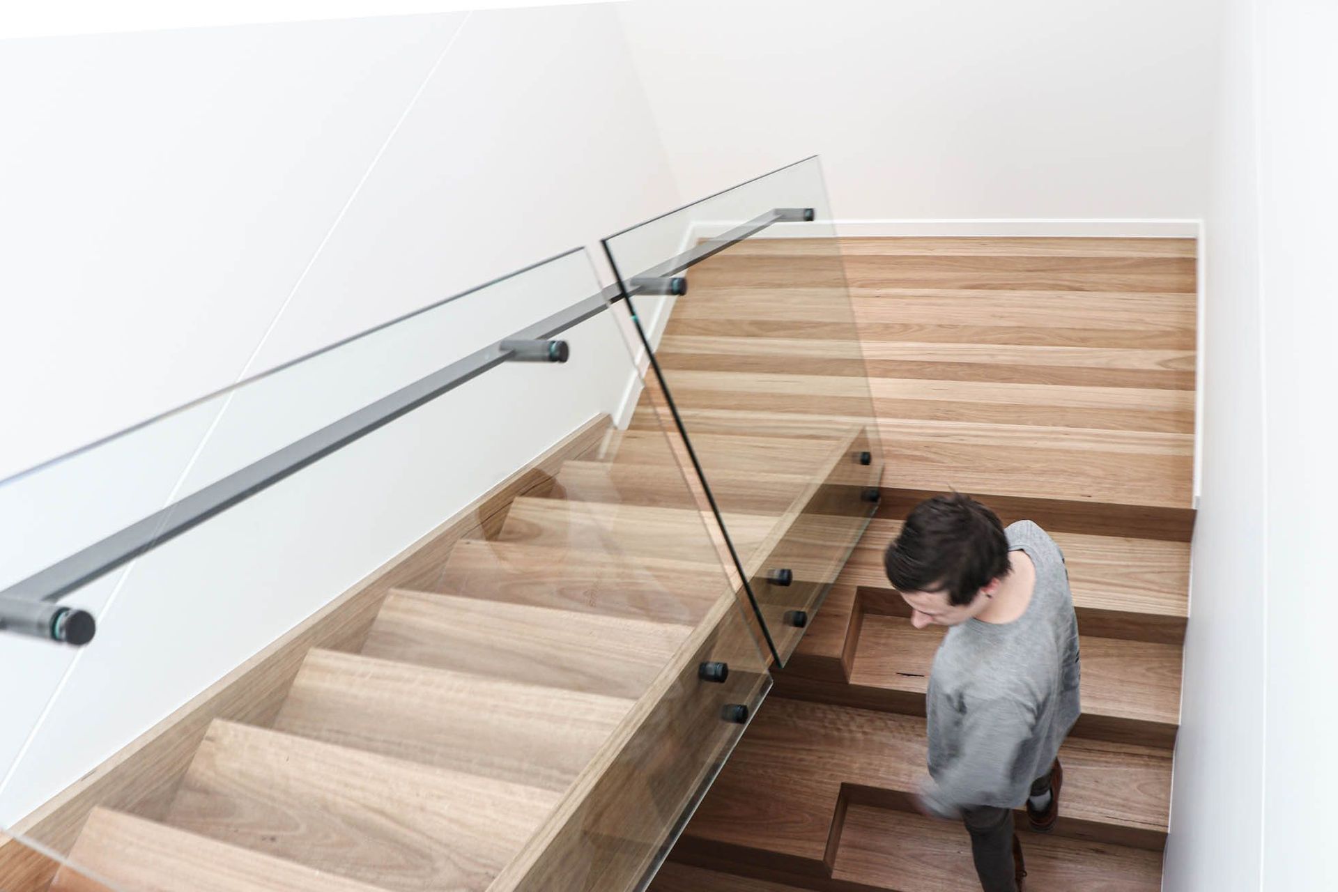 Anderson Residence - Staircase. Glass balustrade and timber stair between white walls.