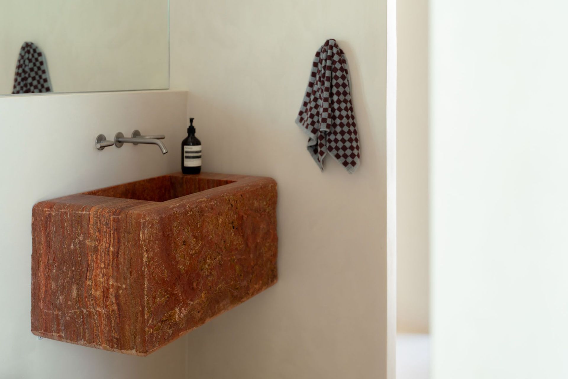 House on Pacific - Powder Room. Carved red stone basin against a soft plaster wall.