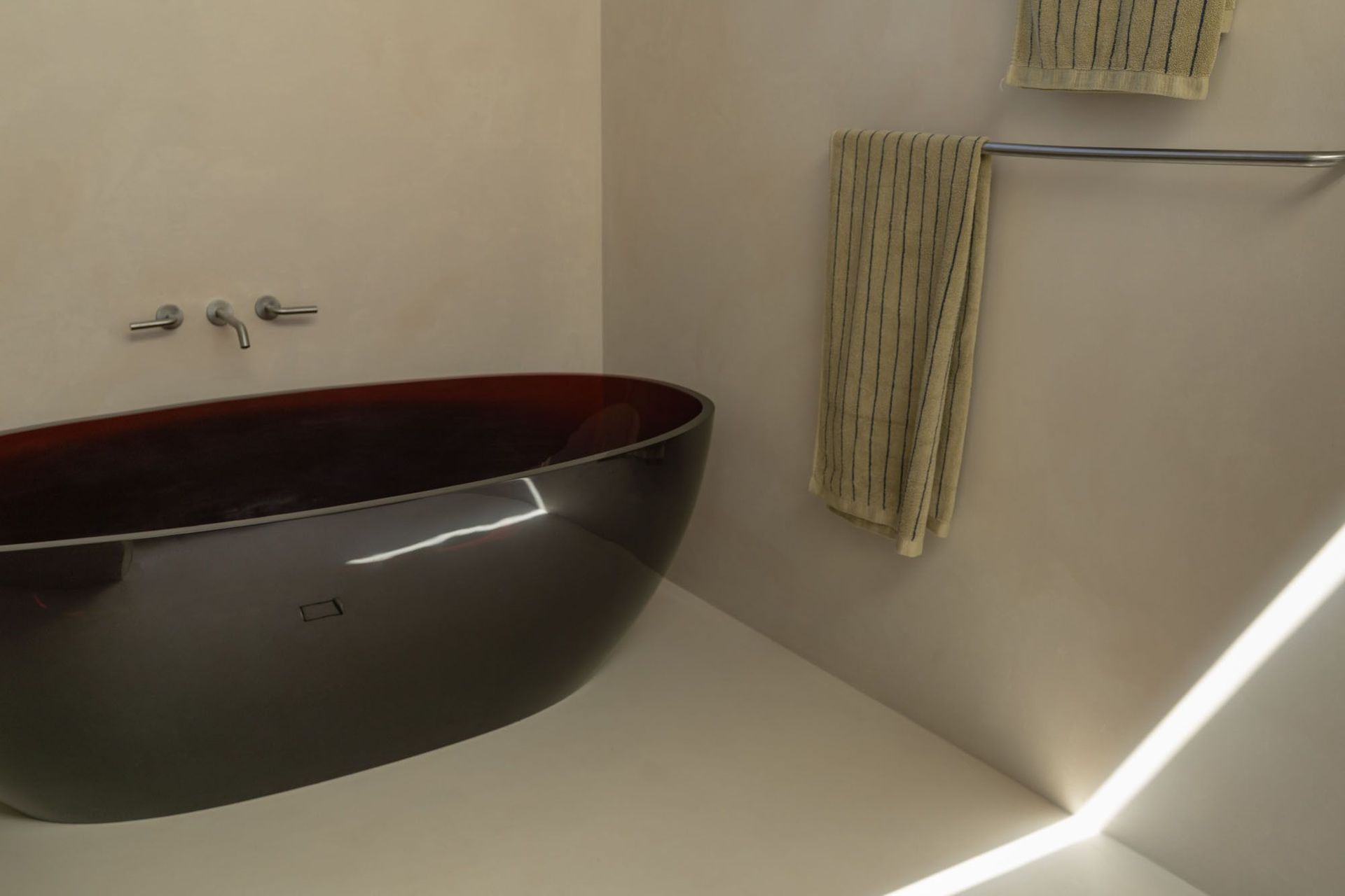House on Pacific - Bathroom. Glossy freestanding bath beneath a skylight slot.
