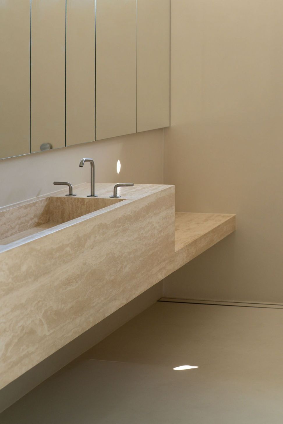 House on Pacific - Bathroom. Floating travertine vanity beneath mirrored cabinetry.