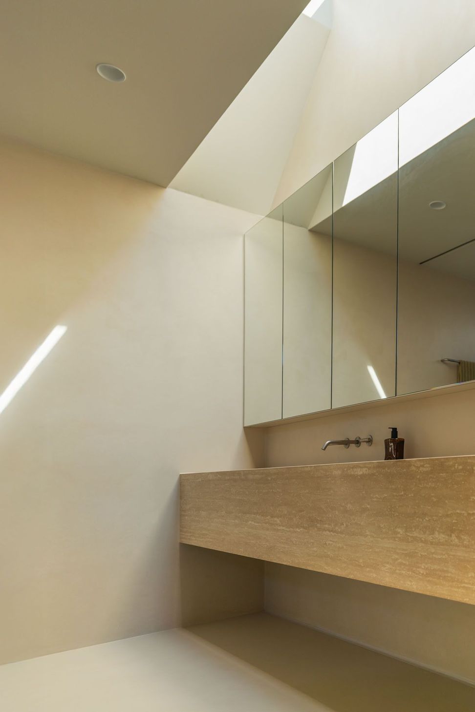House on Pacific - Bathroom. Stone vanity with a hidden skylight casting light across the wall.