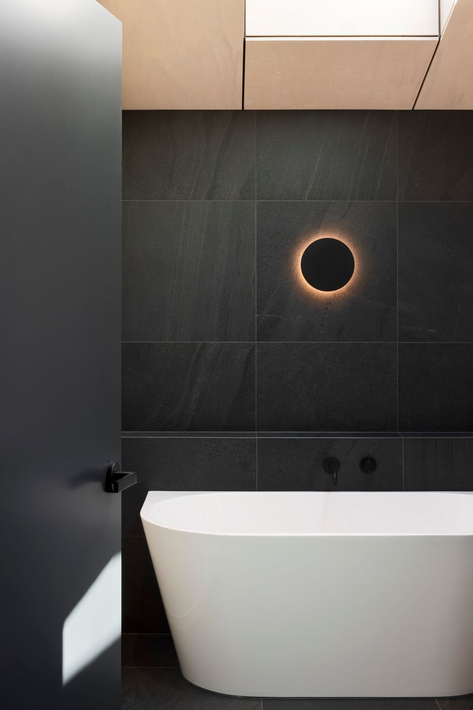Natural timbers give way to dark stone tiles in the bathroom for a modern twist on the classic 'black and white' look.