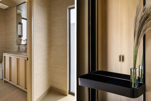 A refined bathroom interior featuring a timber vanity with integrated basin, tall mirror, textured beige wall finish, warm timber ceiling and floor tones, and a narrow vertical window. In the foreground, a glossy black wall-mounted console or basin-like fixture contrasts with dark vertical framing and decorative glass vases with dried grasses. The overall composition is warm, contemporary, and highly detailed.