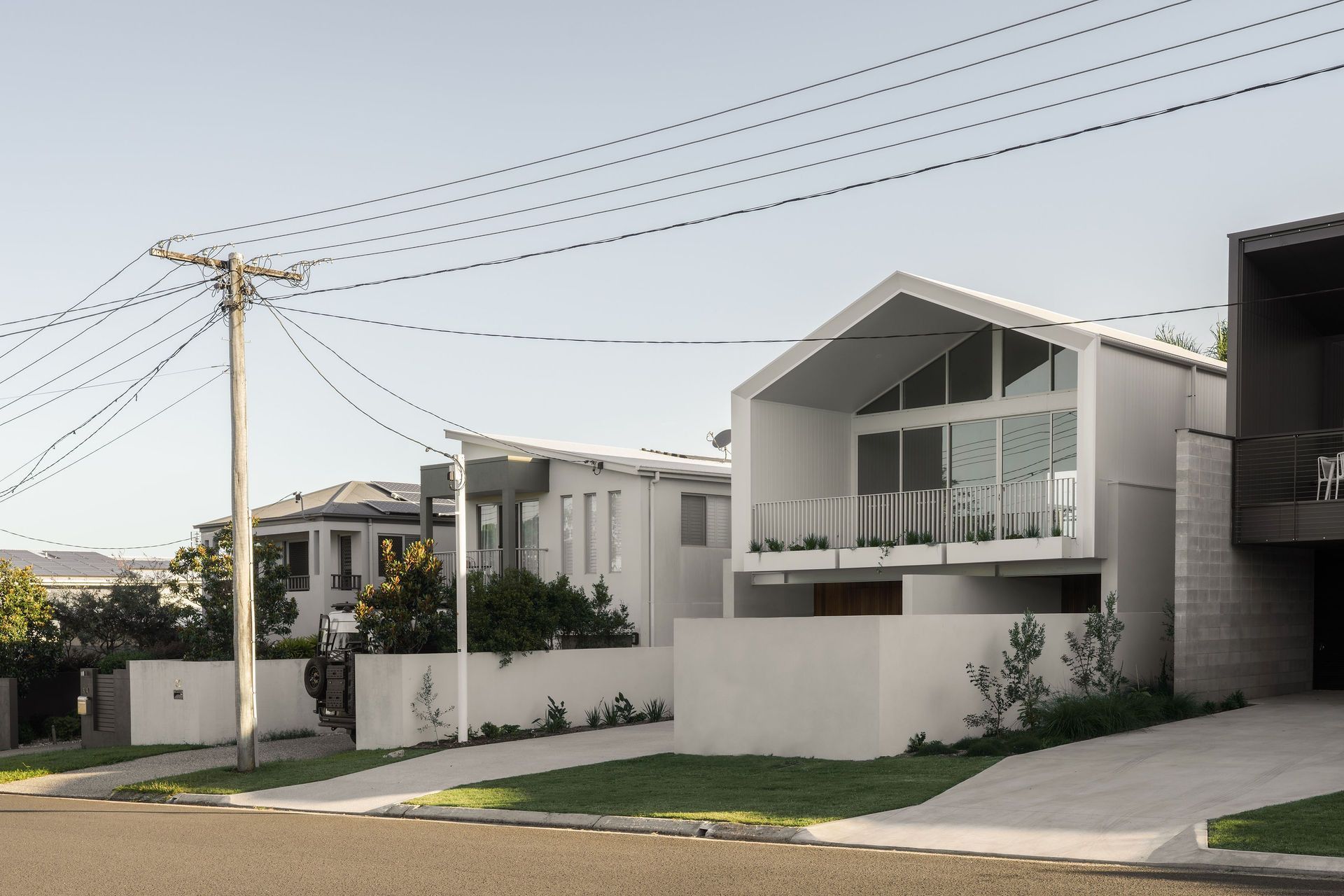 Gilbert Residence - Exterior. Street view of the gabled home with white render and dark cladding.