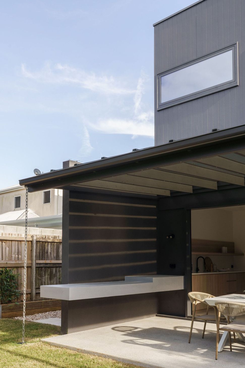 Gilbert Residence - Patio. Covered outdoor area with dark cladding and a timber soffit.
