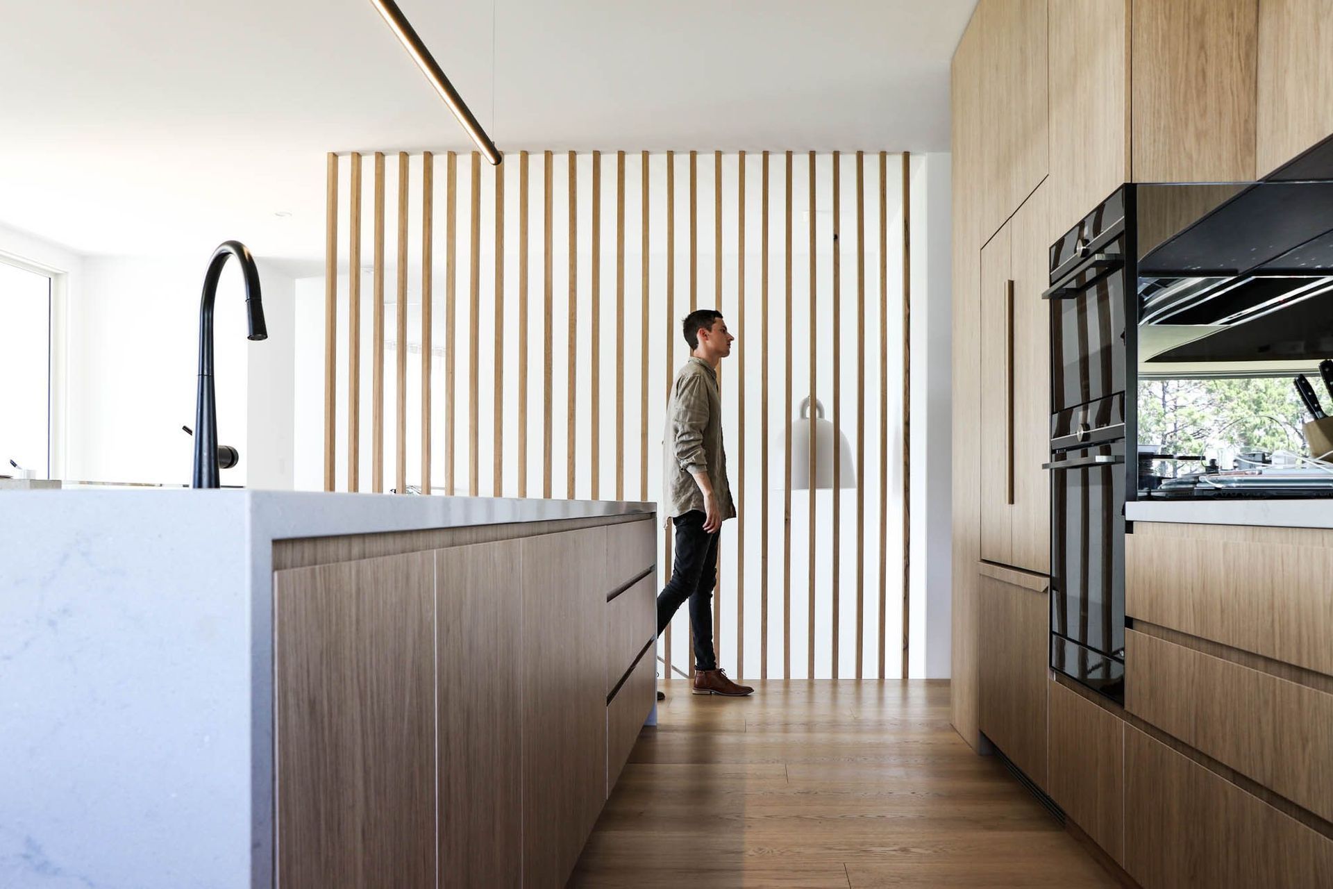 Shipp Residence - Kitchen. Kitchen with a stone island and timber battened joinery.