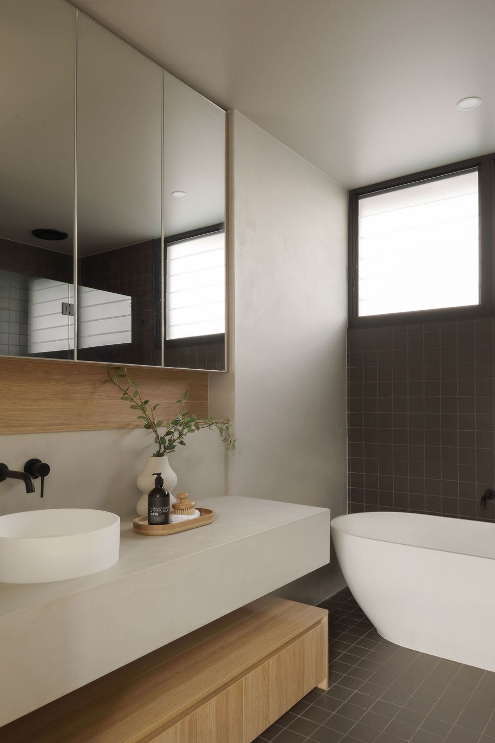 Gilbert Residence - Bathroom. Stone vanity with black tapware and a vase of greenery.