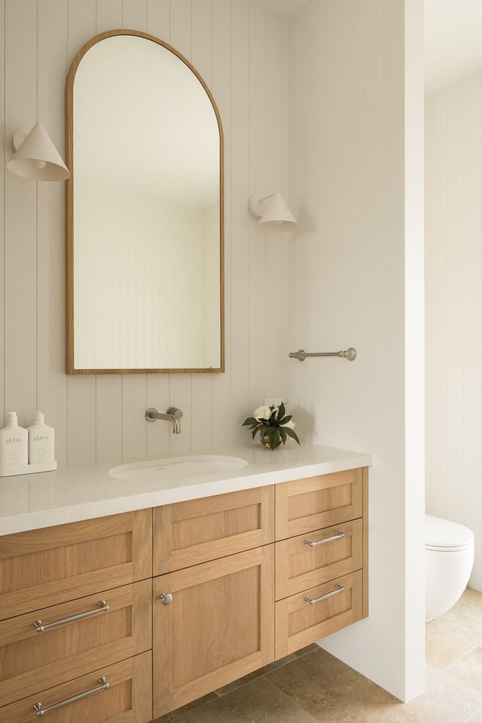 Euroa Farm - Bathroom. Vertical boarded walls and an arched mirror above the vanity.