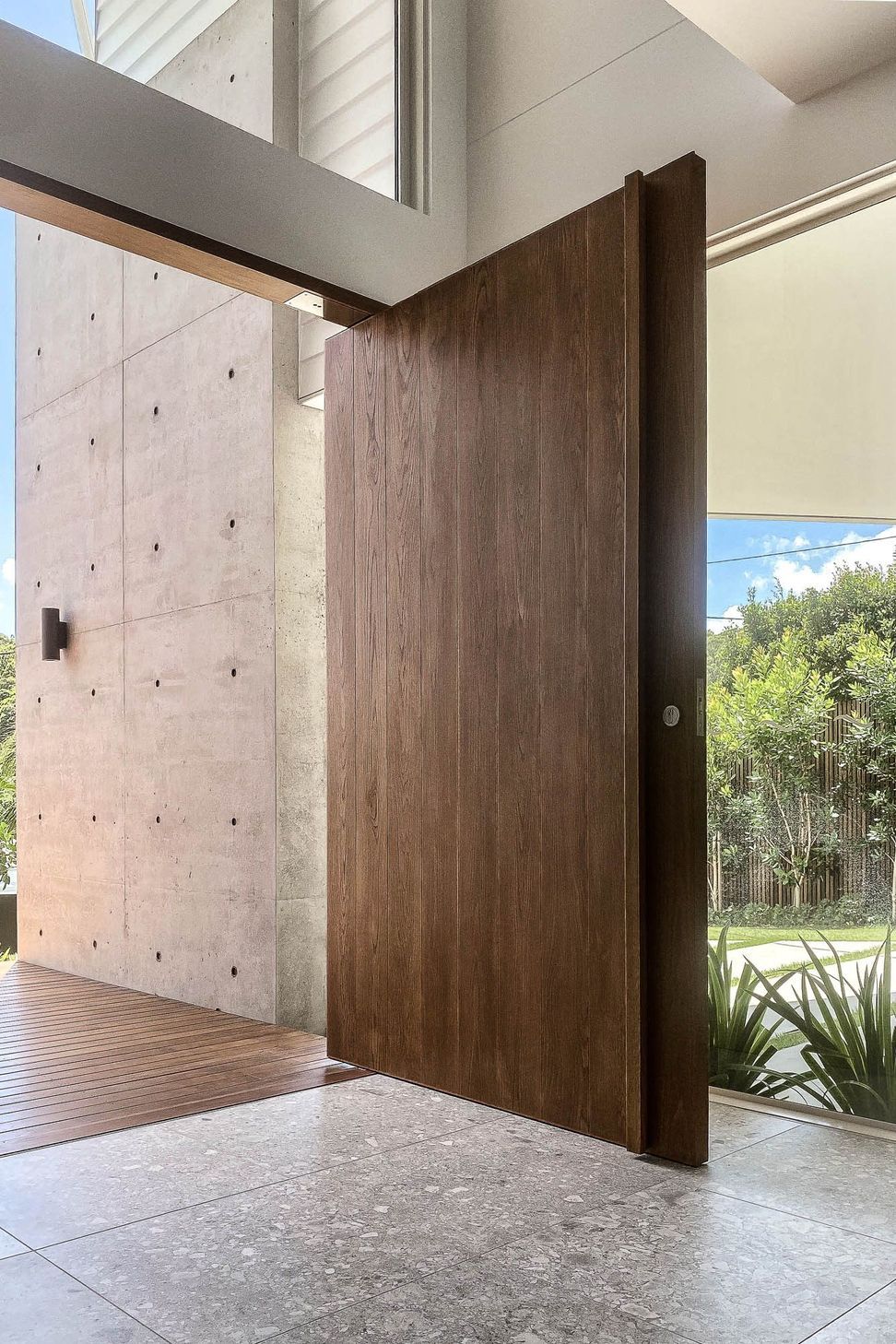 Shipp Residence - Entry. Off-form concrete wall beside a timber door with garden views.