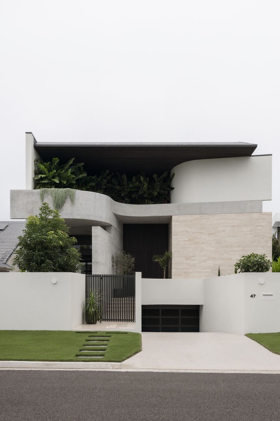 Carwoola House - Exterior. Sweeping curved concrete upper level above a stone clad entry.