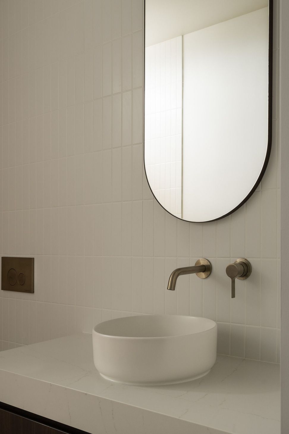 Carwoola House - Powder Room. Brushed tapware below a round mirror on textured walls.