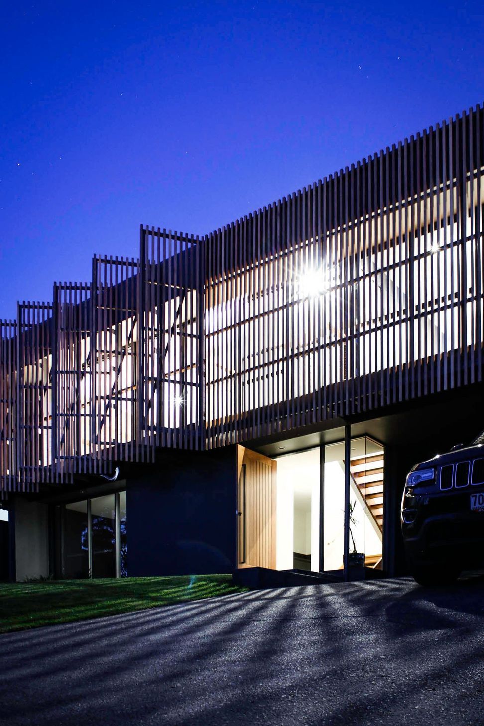Glennon Residence - Exterior. Battened screens lit from within at twilight.