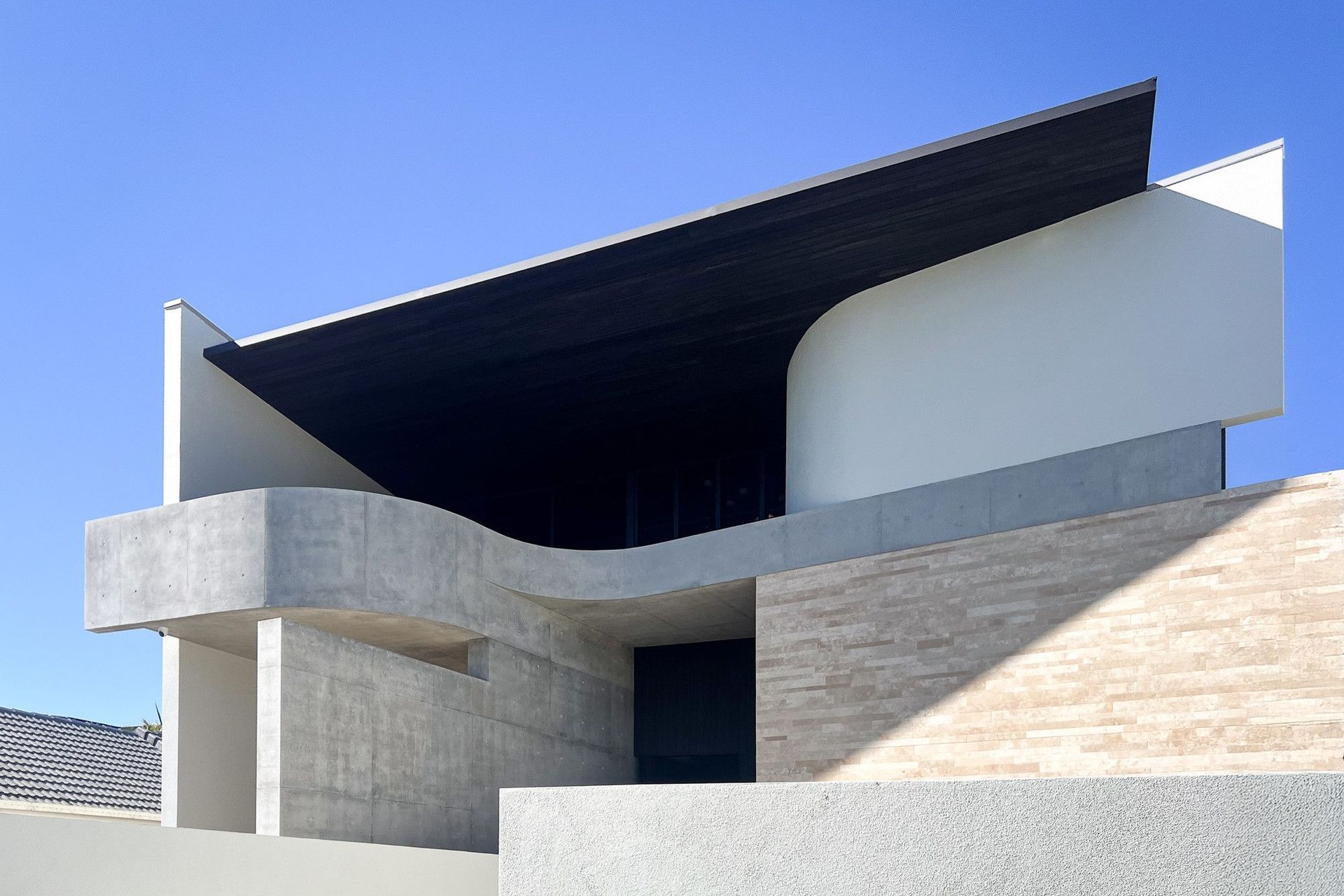Carwoola House - Exterior. Curved concrete roof edge against a clear blue sky.