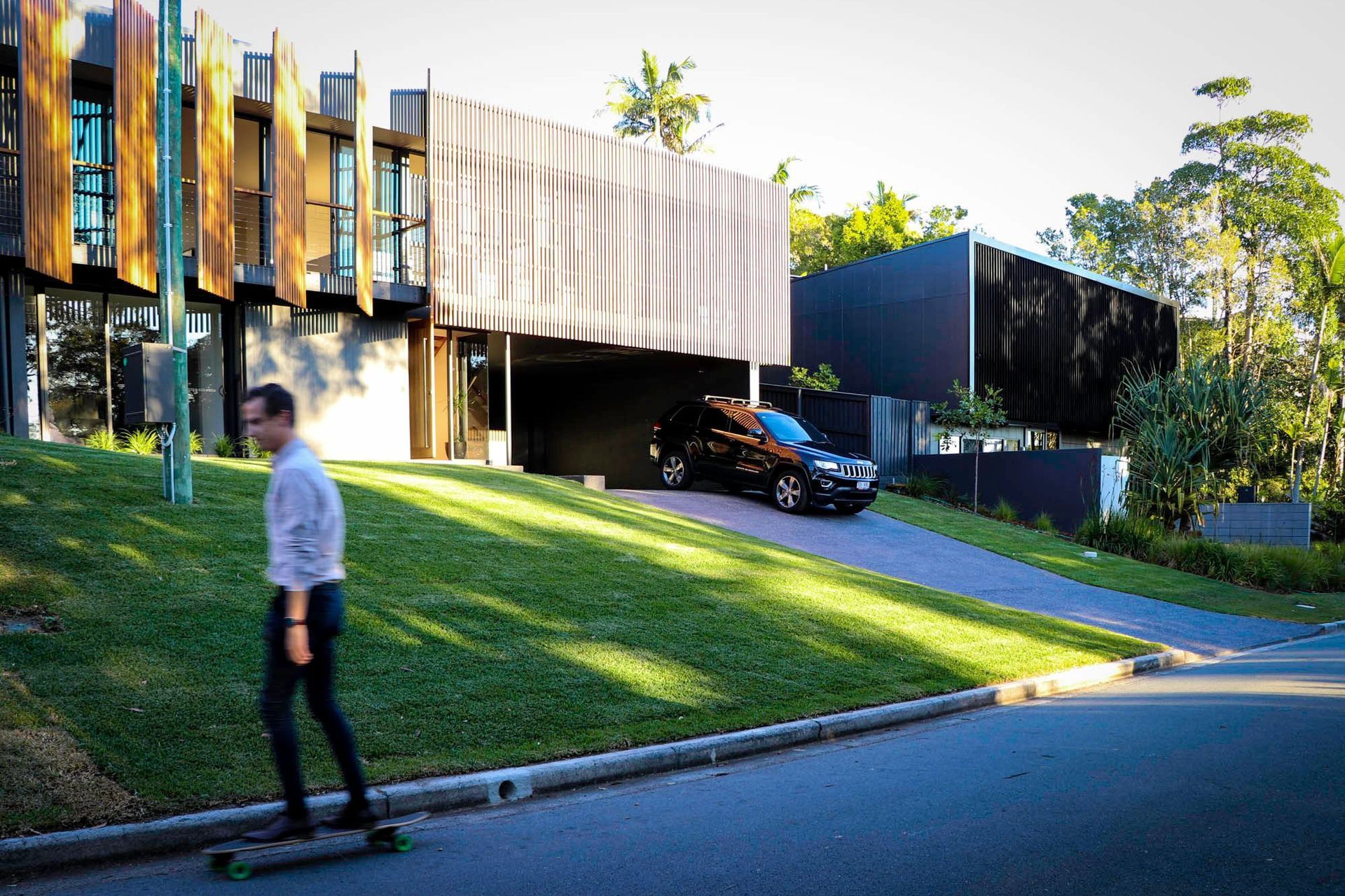 Glennon Residence - Exterior. Sloping lawn leading up to the battened facade.