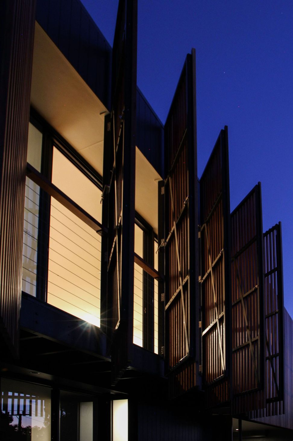 Glennon Residence - Exterior. Night view of the screens framing lit windows.