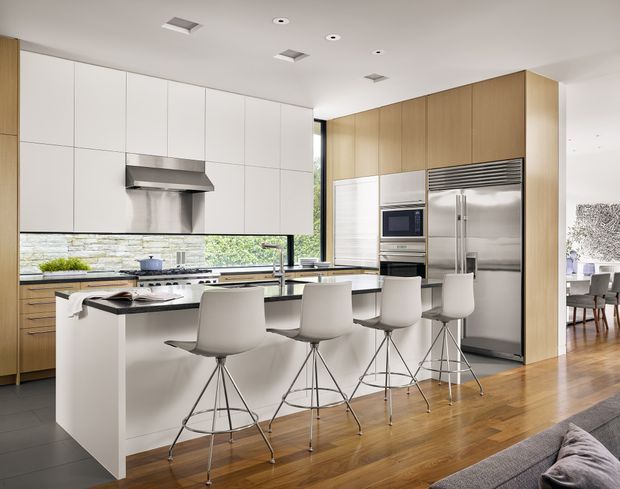Bright contemporary kitchen with a large white island and four bar stools, extensive white and light timber cabinetry, stainless-steel appliances, and a narrow stone or tile backsplash. A dining area is visible beyond the kitchen, with timber flooring continuing through the open-plan space.