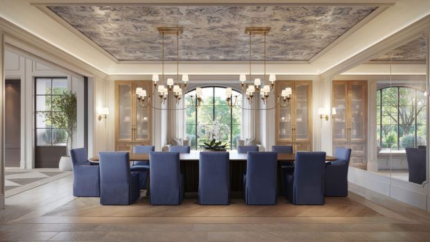 Elegant formal dining room with a long dark dining table surrounded by blue upholstered chairs. The room features extensive built-in cabinetry, mirrored wall panels, large windows, ornate multi-light chandeliers, pale classical wall mouldings, and a highly decorative patterned ceiling panel. Warm timber flooring and abundant natural light create a refined, traditional atmosphere.