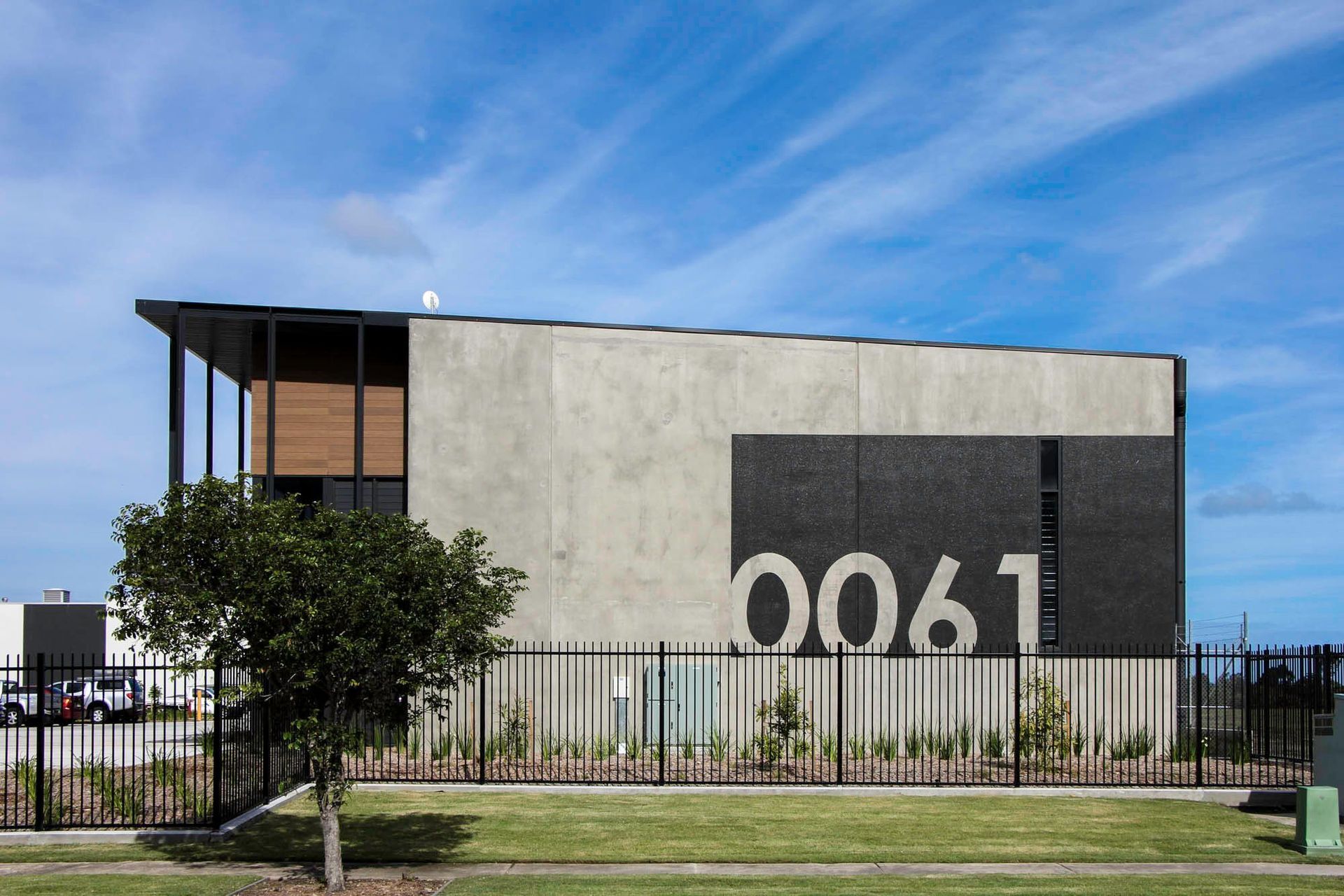 Eniquest Warehouse - Exterior. Street frontage with the building number and young landscaping.