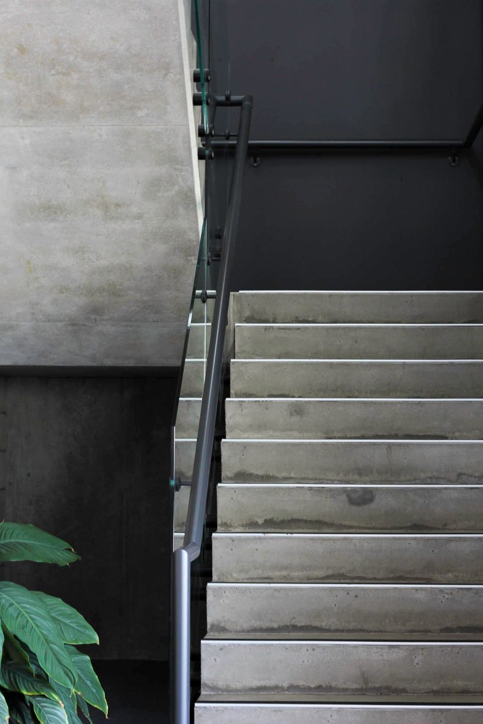 Eniquest Warehouse - Staircase. Concrete stair with a slim steel handrail.