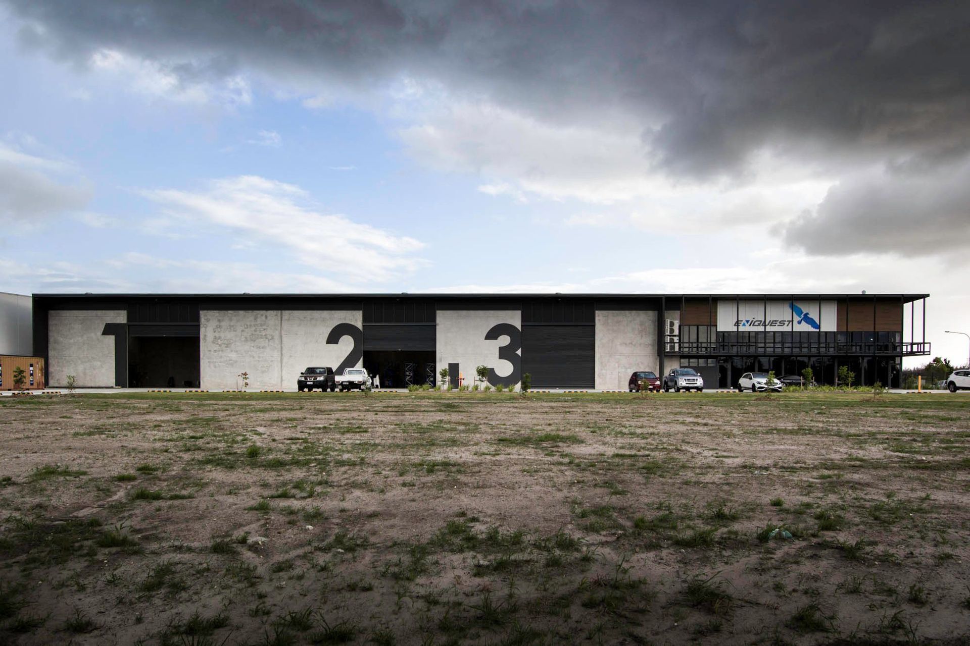 Eniquest Warehouse - Exterior. The warehouse across open ground beneath a dramatic sky.