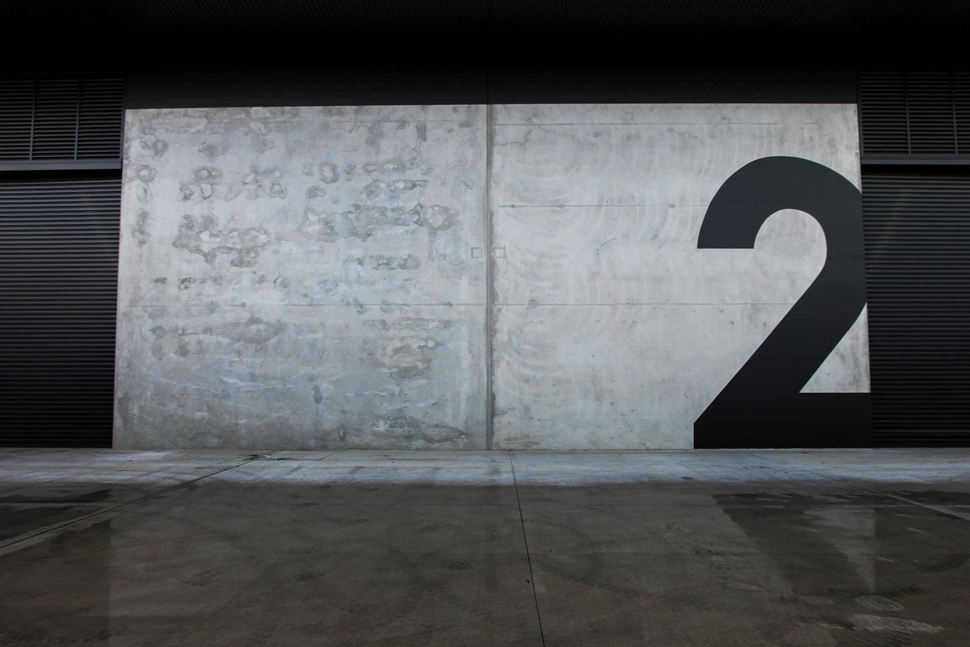 Eniquest Warehouse - Exterior. Concrete panel tenancy with a painted number.