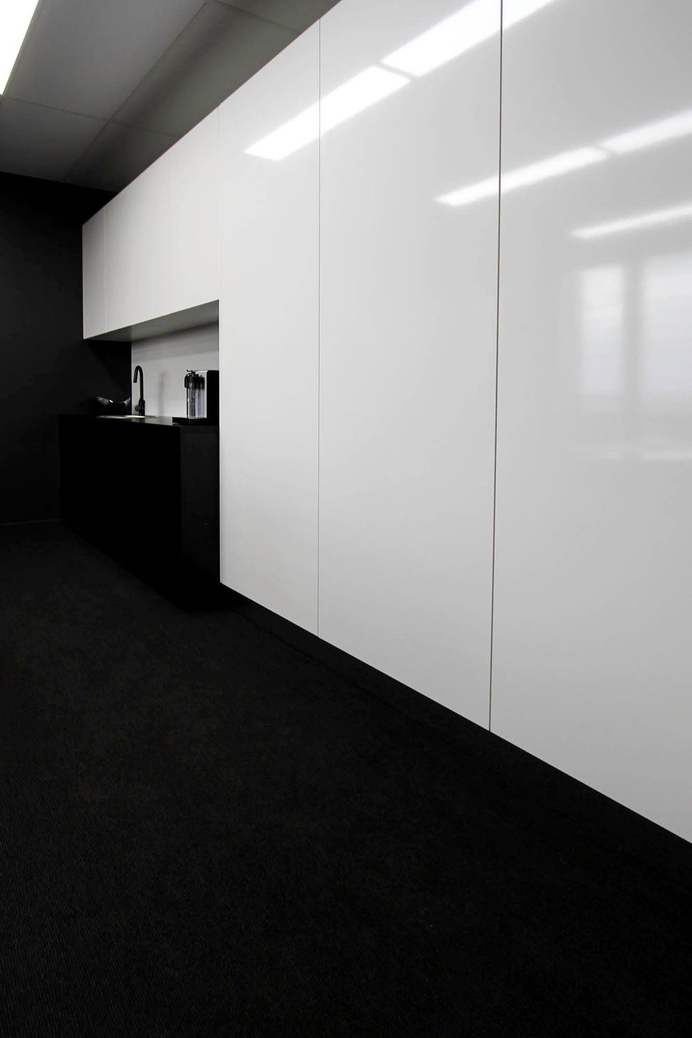 Eniquest Warehouse - Kitchen. Kitchenette with white joinery and a black benchtop.