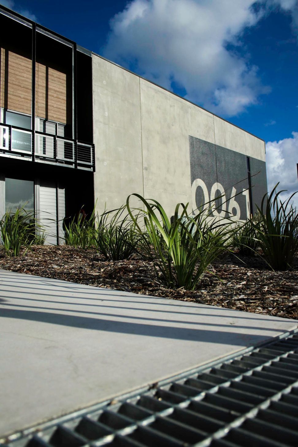 Eniquest Warehouse - Exterior. Building number and native planting at the entry.