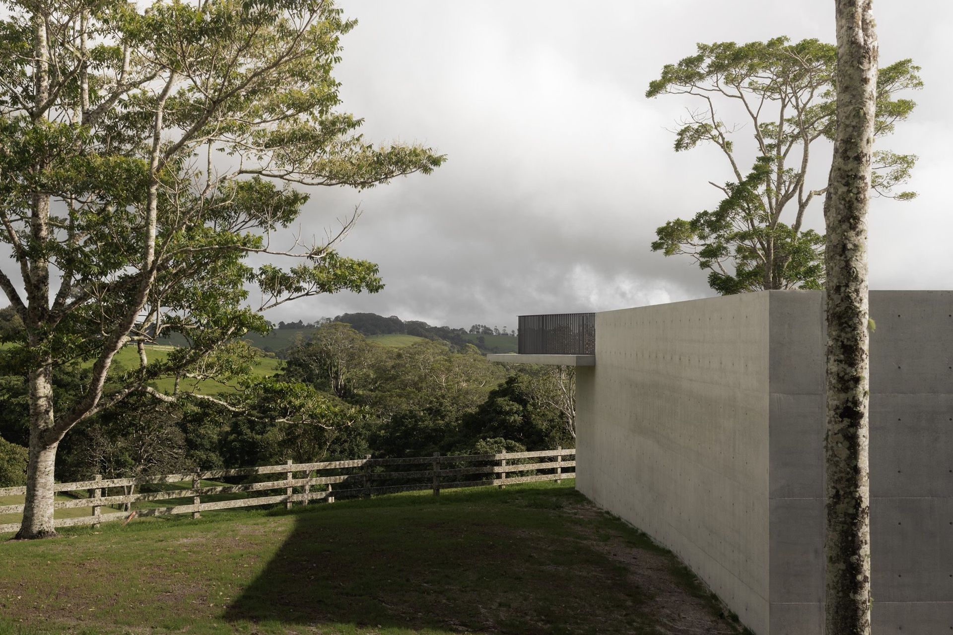 The Farm - Exterior. Tall concrete walls rising beside mature gums.