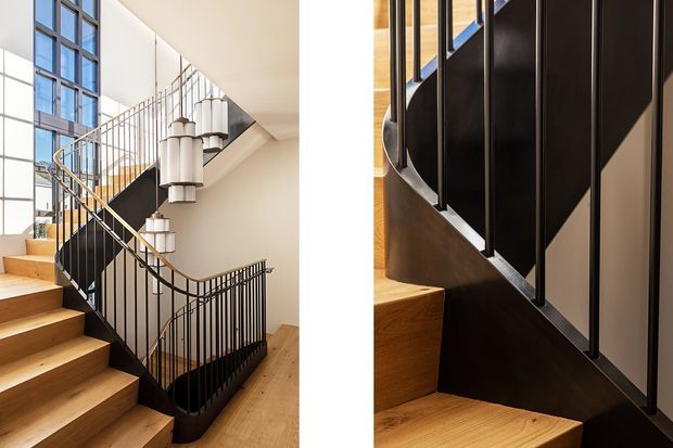A split-view architectural photograph highlighting a sculptural interior staircase. The main view shows warm timber treads, black metal balustrades, a curved stair edge, tall multi-pane glazing, and distinctive cylindrical pendant lights. The detail view focuses on the black metal railing, dark stair stringer, and timber stair construction.