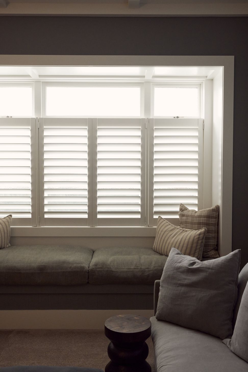 The built-in window seat in the media room — plantation shutters, layered cushions and a quiet corner to settle into. Point Chevalier Bungalow, in collaboration with Hannah Warren Interiors.