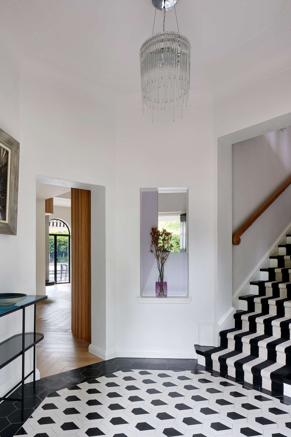 Large black and white art deco entryway with geometric concrete matt tiling from Perini, matched with black and white stairway carpet runner. The project is a 1930s art deco spanish mission style house in Melbourne. See more from our Arch Deco Project.