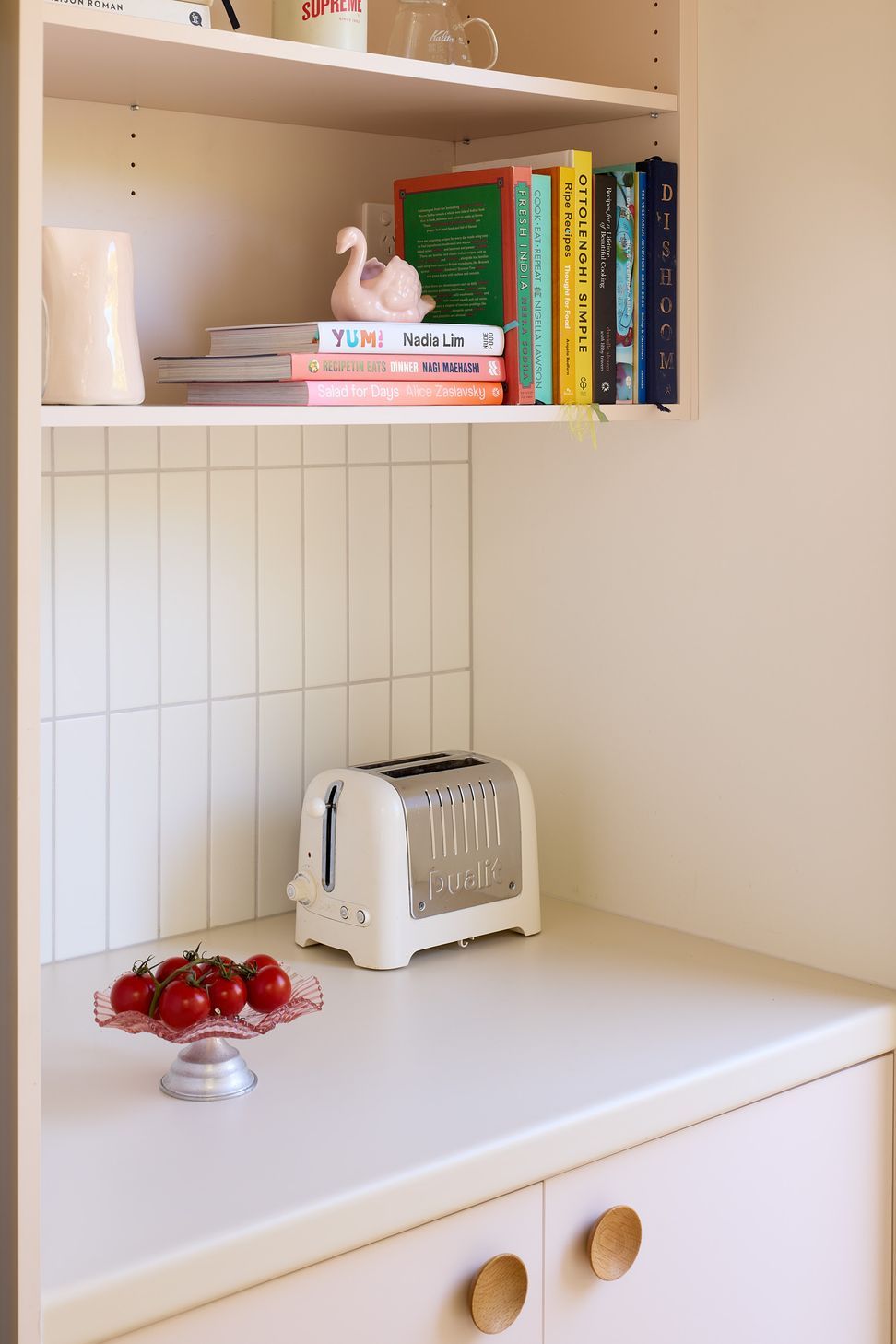 The adjoining scullery mirrors the laundry's carefully selected material palette, pairing soft pink cabinetry with warm neutral surfaces and brass detailing to create a cohesive extension of the kitchen.