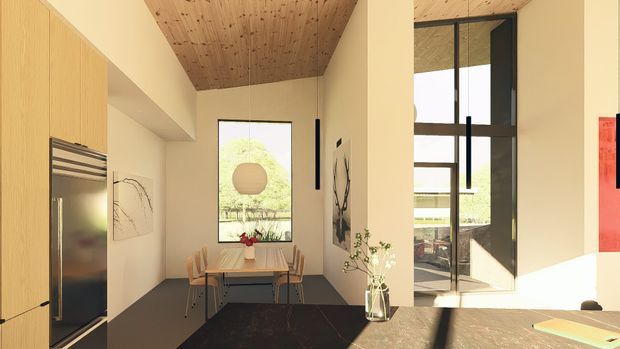 A refined open-plan kitchen and dining area with warm timber cabinetry, a dark stone kitchen island, a timber-lined ceiling, and a compact dining table positioned beside a large window. Full-height black-framed glazing and a glazed door bring in strong natural light, while simple black pendant lights and minimalist artwork add contrast.