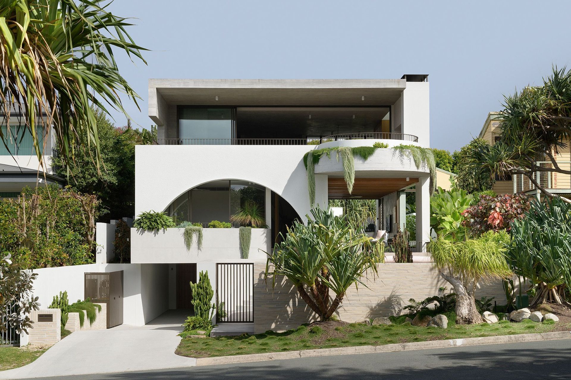 Villa Solare - Exterior. White rendered facade with a sweeping arch and trailing planting.