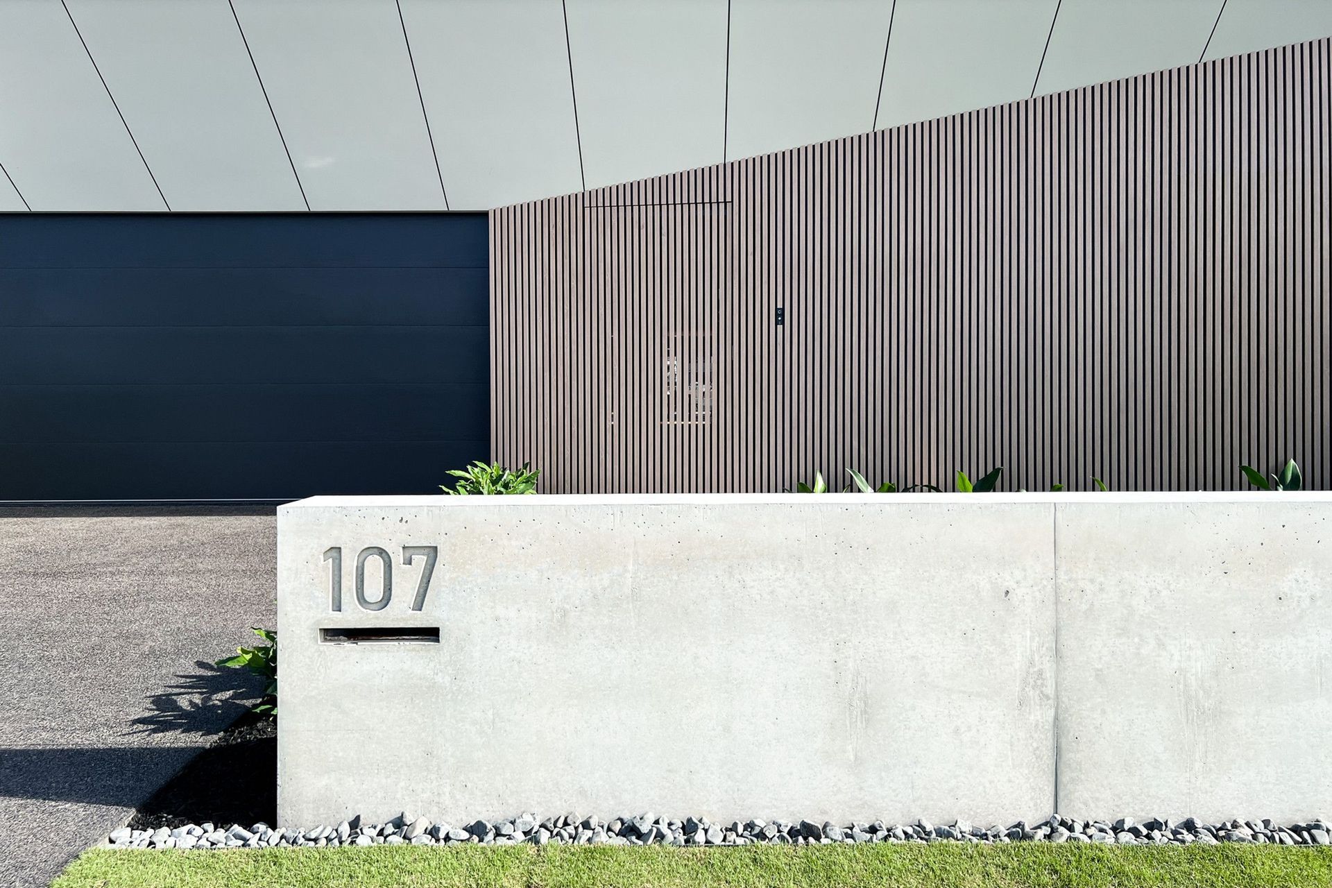 Bells Esplanade - Exterior. Off-form concrete house number wall beside timber cladding.