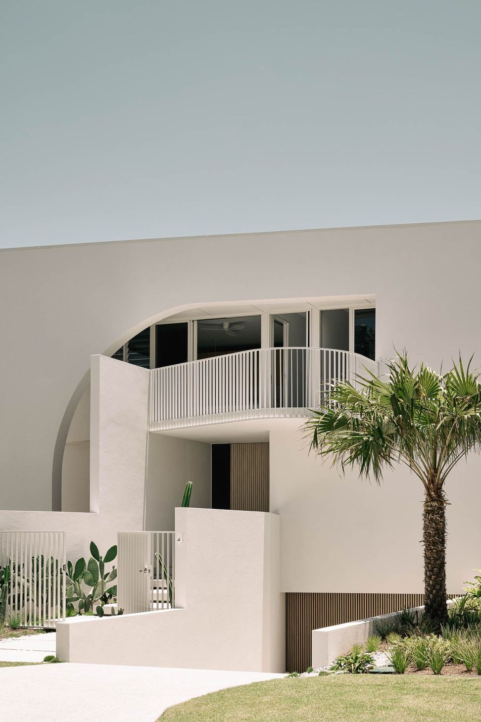 Zaremba Residence - Exterior. Sculpted white facade with a curved parapet and palm.
