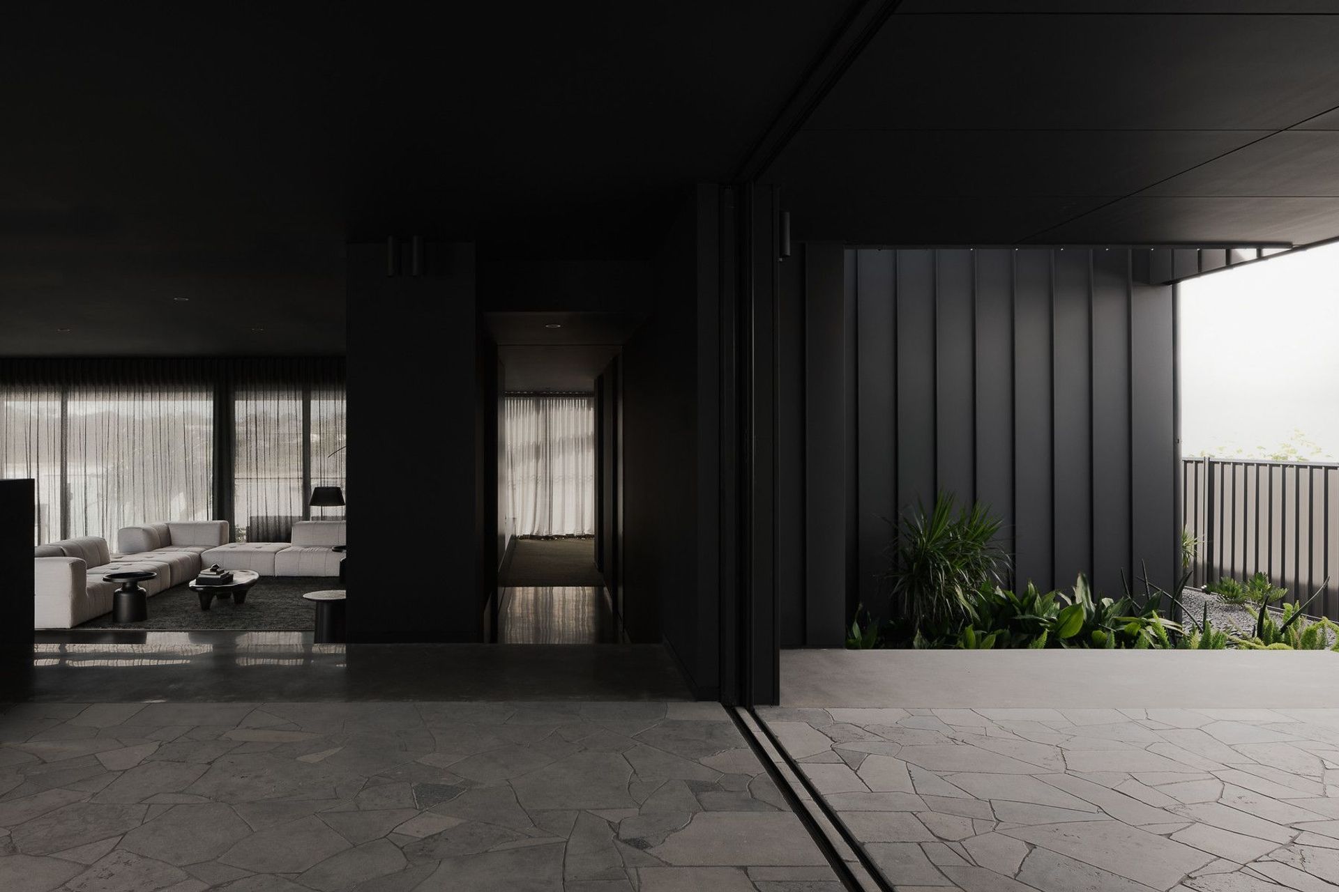 0042 Residence - Living Room. Dark joinery and a planter framing the view through to the courtyard.