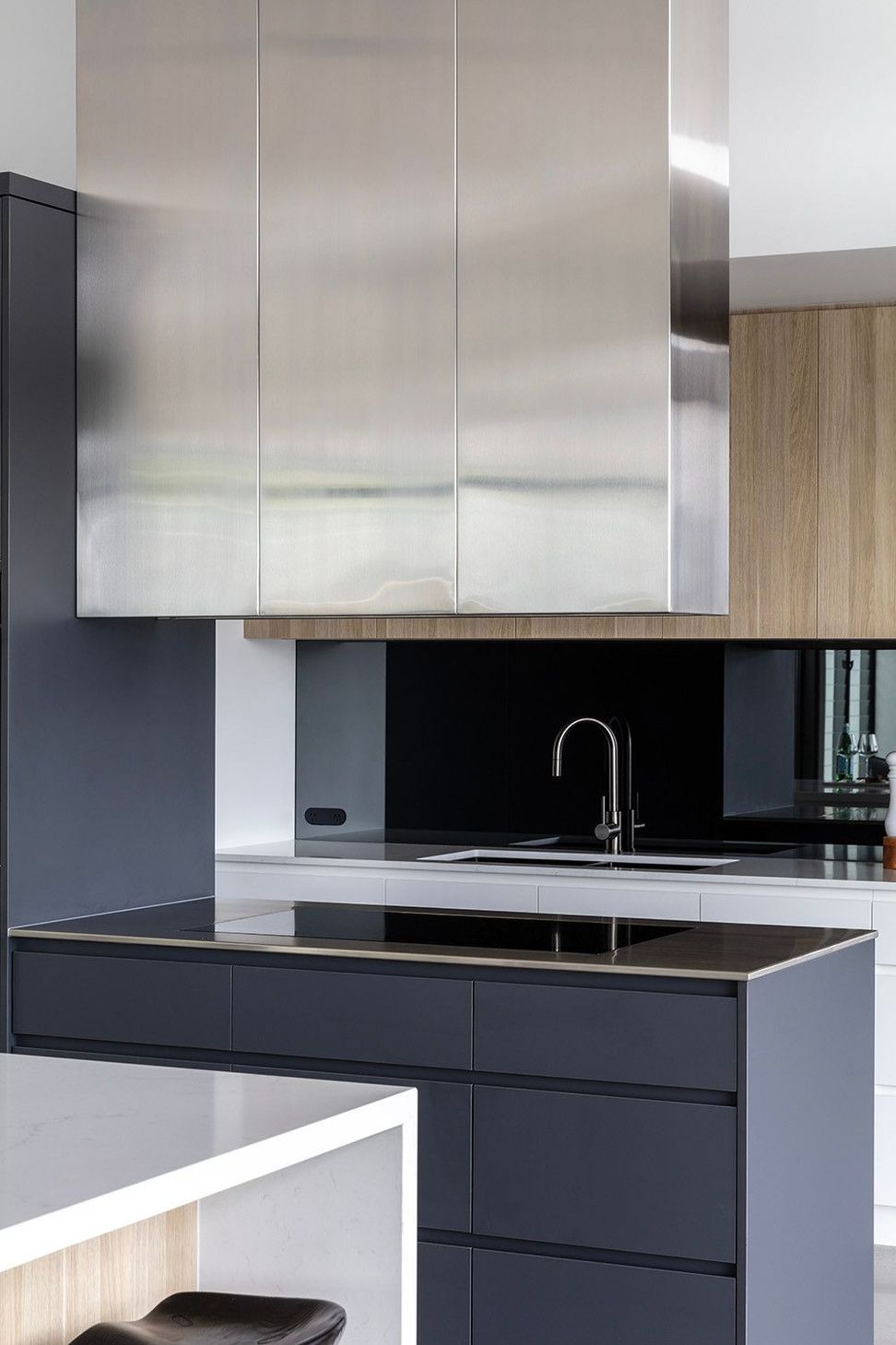 Bells Esplanade - Kitchen. Black tapware and splashback beneath white cabinetry.